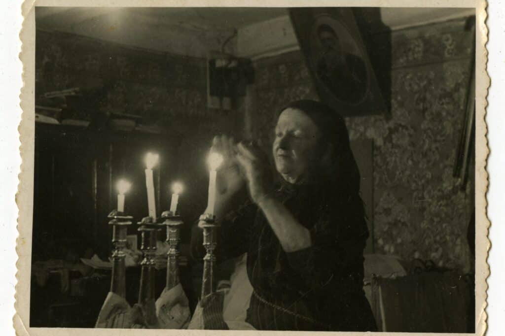 An archival photograph of a woman blessing candles. Photo Credit: The Gottesman Collection, Avrom Yosel Rotenberg and Simcha Rotenberg.